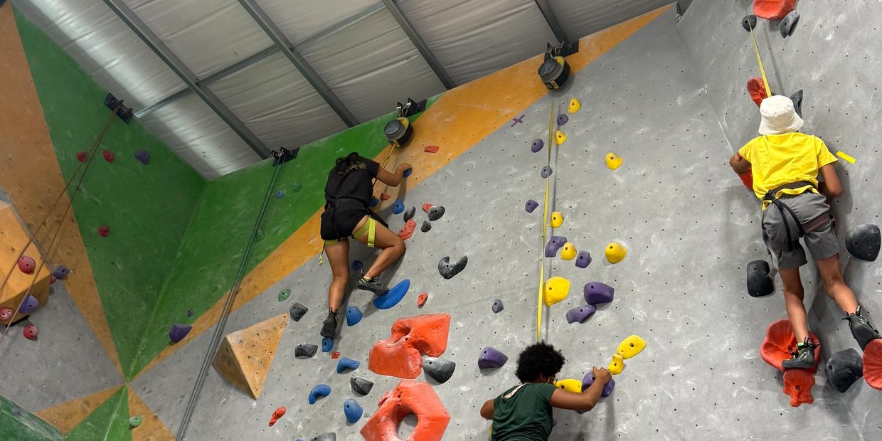 People climbing an indoor rock climbing wall.