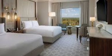 Modern hotel room with two beds and a large window view.