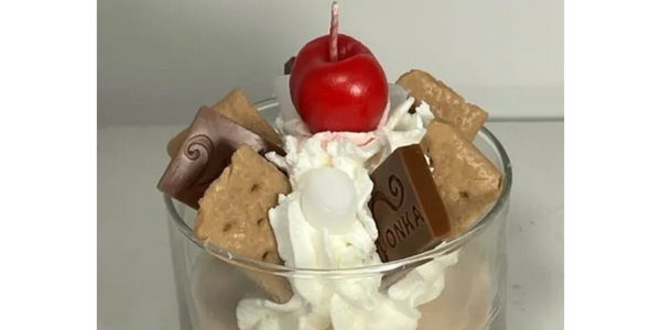 a candle glass with chocolates and cherry 