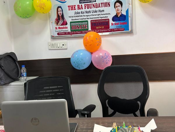 Office setup with a rainbow cake, balloons, and a foundation banner on the wall.