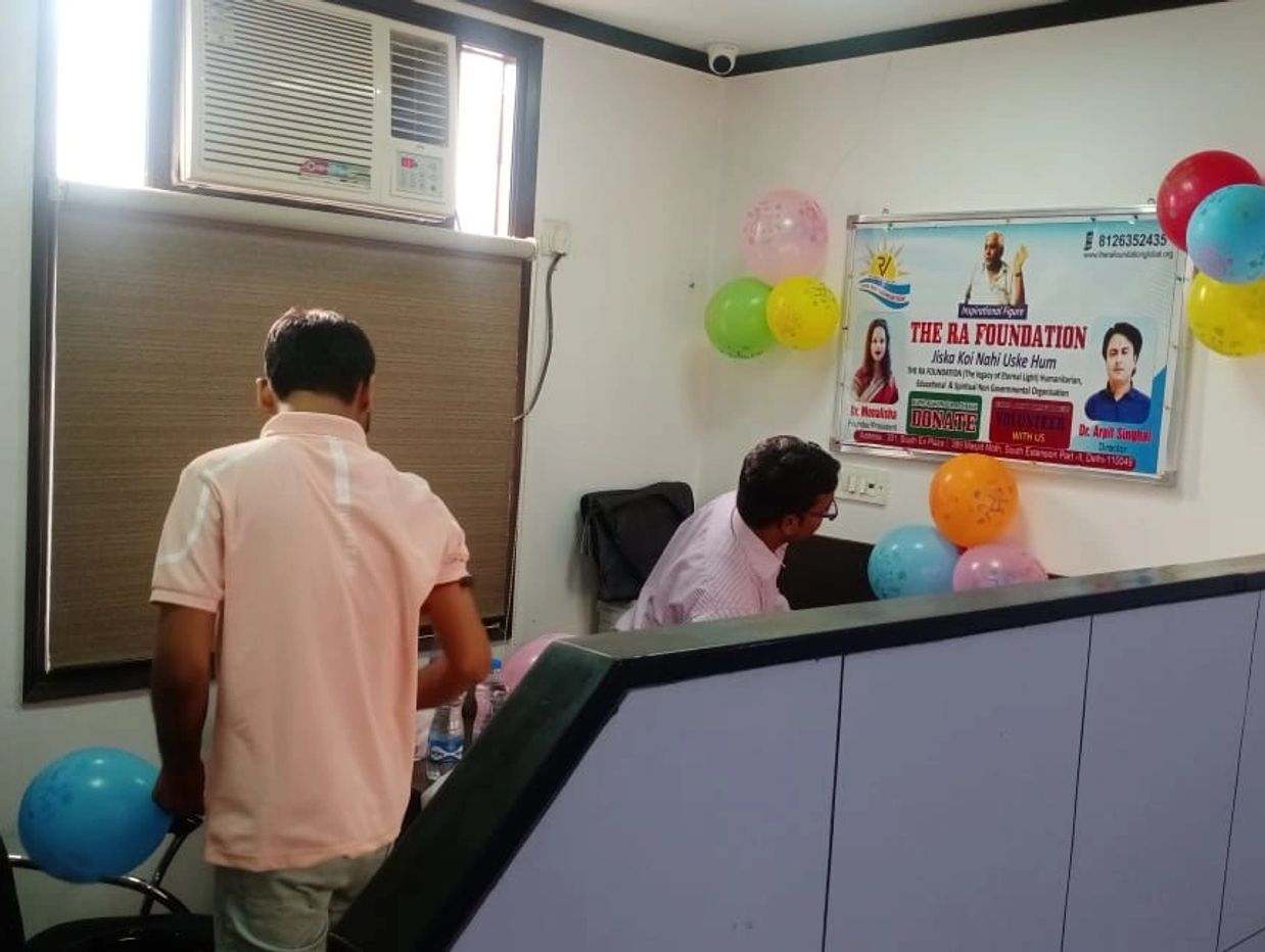 People preparing for an event at The RA Foundation office decorated with colorful balloons.