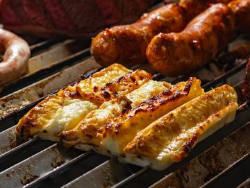 Queso asado en brochetas junto a embutidos en parrilla.