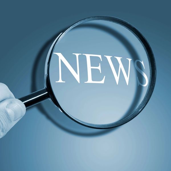 Magnifying glass enlarges the word NEWS on a blue background.