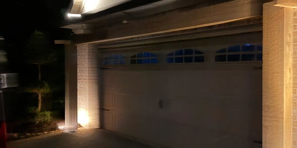 Lit garage door at night on a suburban house.