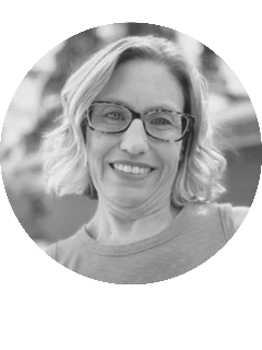 Smiling woman with glasses, short blonde hair.