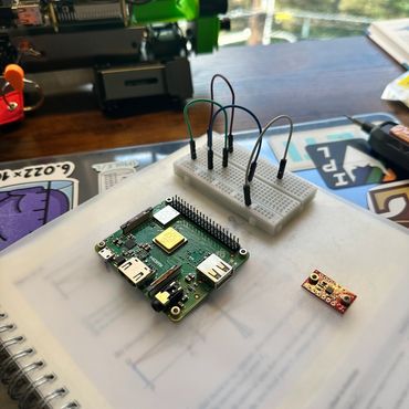 Raspberry Pi Zero with a breadboard and connected jumper wires on a notebook.