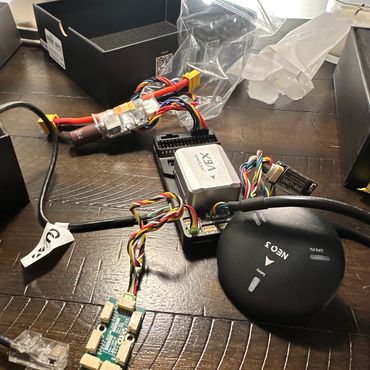 Electronic drone components including a VTX and GPS module on a wooden table.