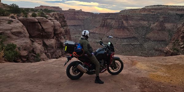 Motorcyclist overlooking a canyon at sunset.