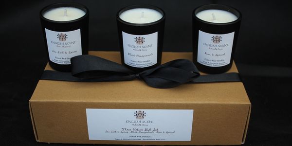 Three scented candles on a gift box with a black ribbon.
