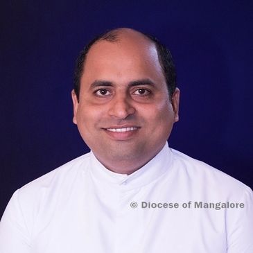 Portrait of a smiling man in white clerical clothing against a dark background.