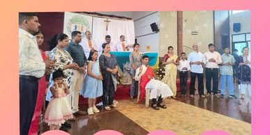 Group of people gathered indoors for a celebration with a pink border.