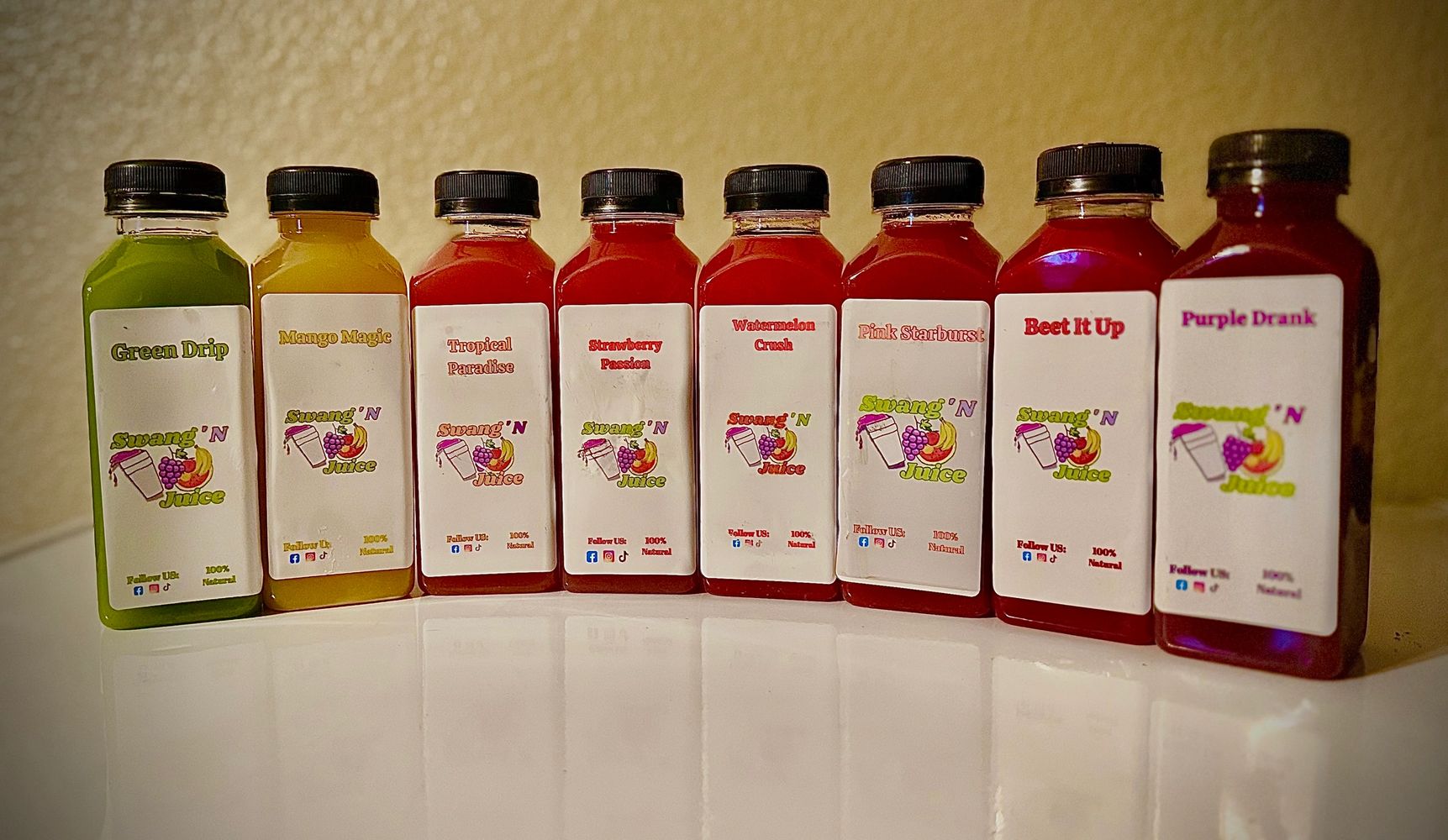A lineup of eight colorful Swang 'N Juice bottles with different fruit flavors.