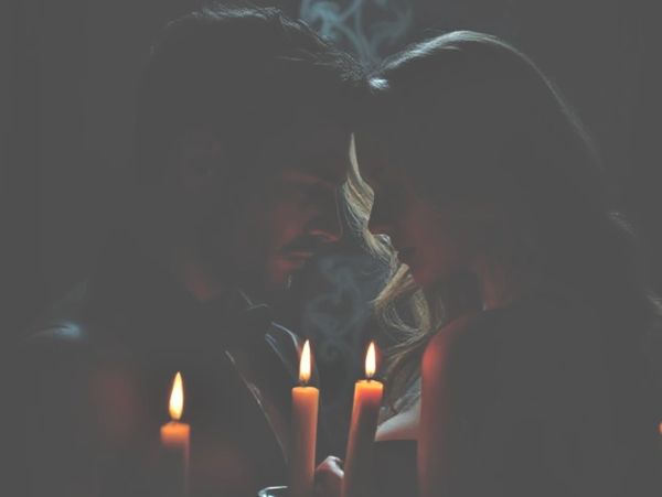 A couple shares a tender moment illuminated by candlelight.