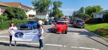 Children hold a banner at a school classic car show parade.
