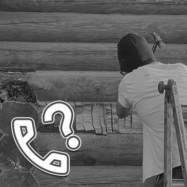 A person repairs a log cabin wall with a hammer while standing on a ladder.
