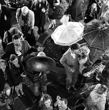 A lively outdoor gathering with people holding umbrellas and musical instruments.