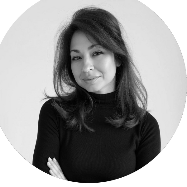 Confident woman with brown hair in a black turtleneck smiles softly against a light background.