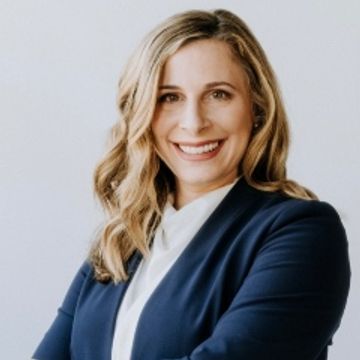 Professional woman in navy blazer smiling confidently.