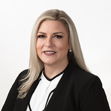 Professional portrait of a smiling woman with blonde hair in business attire.