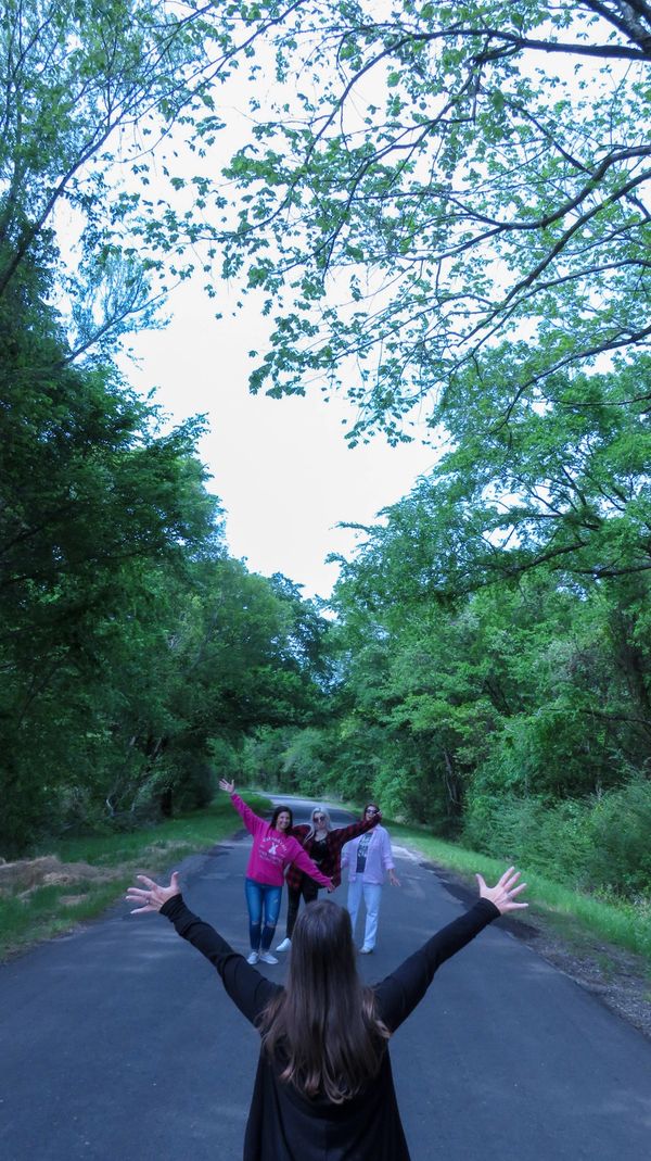 Friends joyfully reunite on a forest path surrounded by lush greenery.