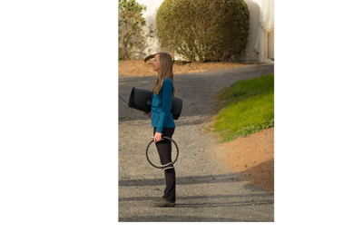 Woman practicing yoga with a yoga mat and ring outdoors on a sunny day.