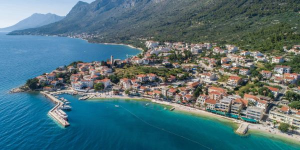 Coastal town nestled between mountains and the sea with a clear blue bay.