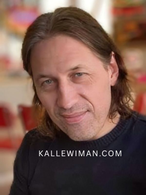 Portrait of a man with medium-length hair and a gentle smile indoors.