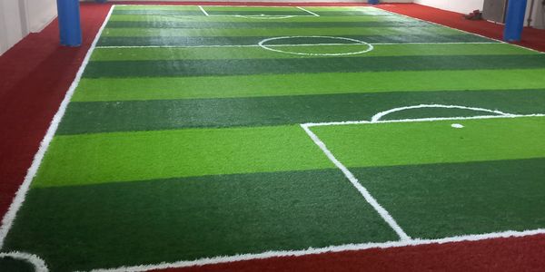 Indoor mini soccer field with artificial turf and bright lighting.