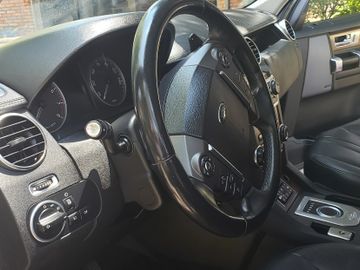 Interior of a Land Rover vehicle focusing on the steering wheel and controls.
