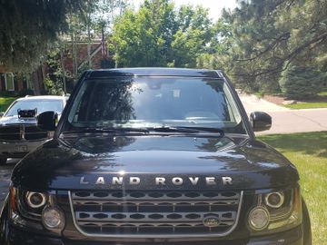 Front view of a black Land Rover parked on a driveway with a Dodge SUV behind it.