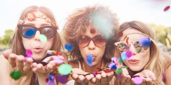 Photo of 3 ladies having fun in front of a photo booth at an outdoor party