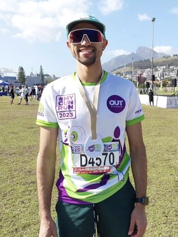 Runner with race bib and medal smiles at event.