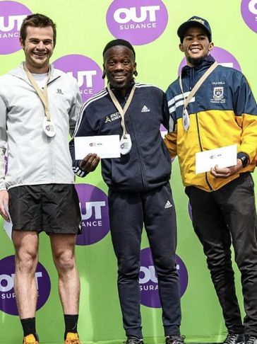 Three athletes pose with medals and awards in front of sponsorship background.