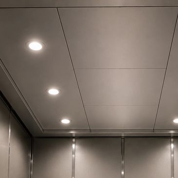Ceiling with recessed lights in a metallic elevator interior.