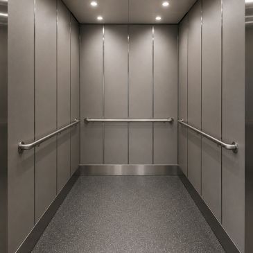 Empty modern elevator interior with metal handrails and overhead lights.