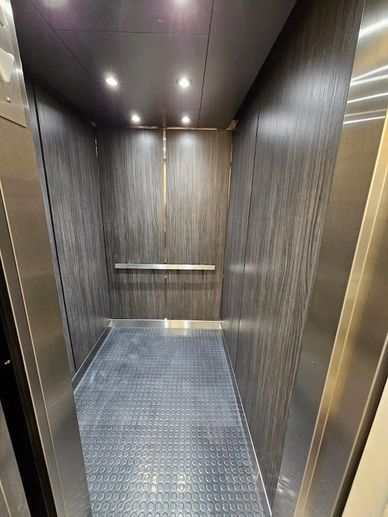 Empty elevator with wood-paneled walls and rubber flooring.