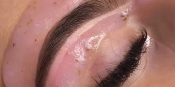 Close-up of glossy, well-groomed eyebrow and eyelashes.