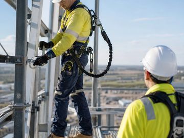 Construction workers in safety gear working on a tall structure.