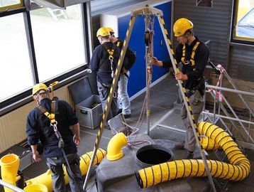 Workers in safety gear inspecting large industrial equipment indoors.