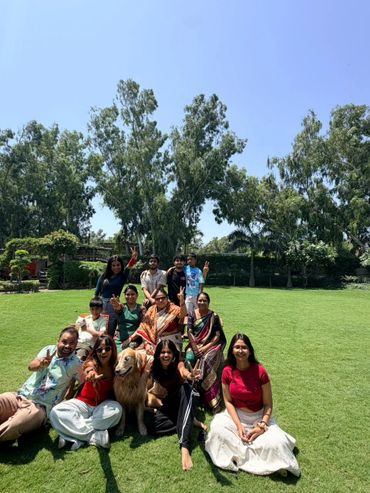 A group of people and a dog enjoying a sunny day in a green park.
