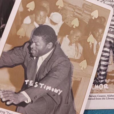 A black man in a suit stands with his arms outstretched and eyes closed in praise during church.