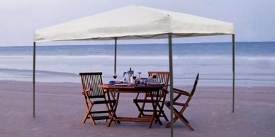 Table and chairs under a white canopy on the beach.
