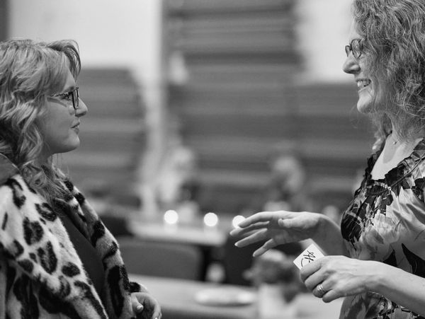 Two women engaged in a lively conversation indoors.