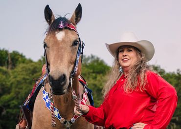 Woman in a red shirt with a horse wearing patriotic decorations.