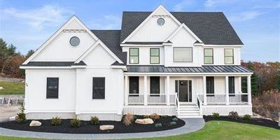 Large white two-story house with a black roof and spacious porch.