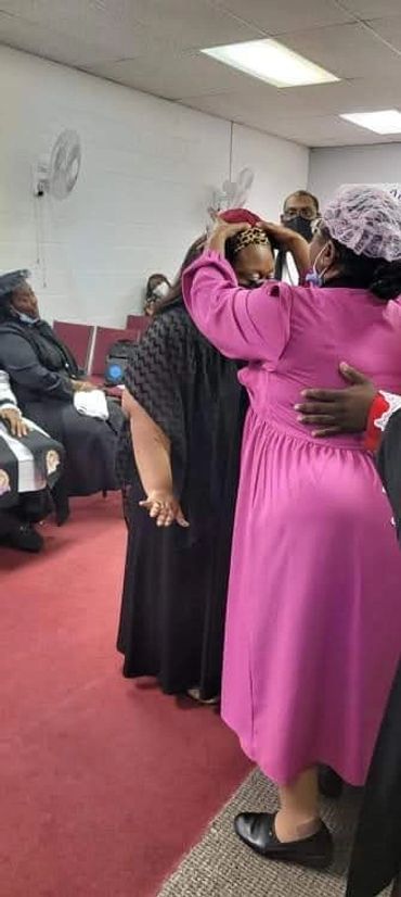 Woman crowning another in a ceremonial setting.