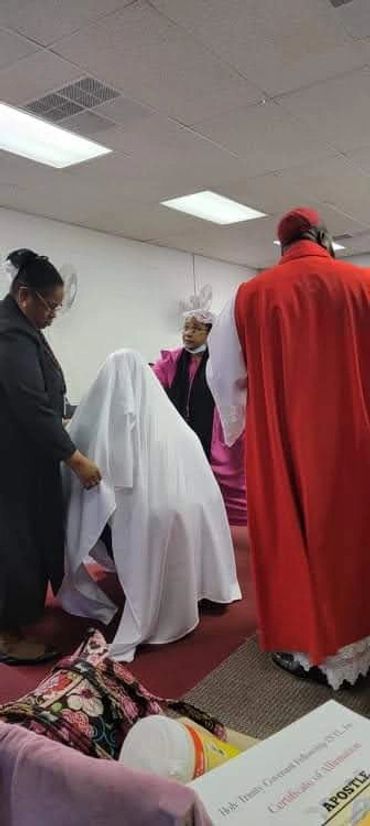 Religious ceremony with a draped figure and clergy members.