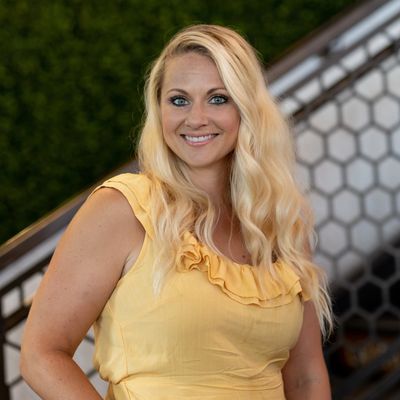 Kristin Martinez, CEM, CMP in a yellow blouse with blonde hair in front of black gradient tile