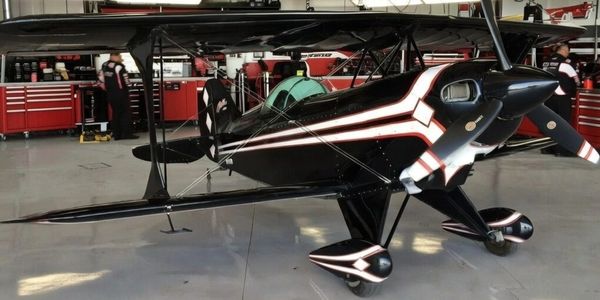 A sleek black and white stunt plane inside a hangar.