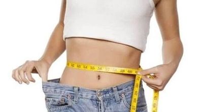 Woman measuring her waist with a tape measure.